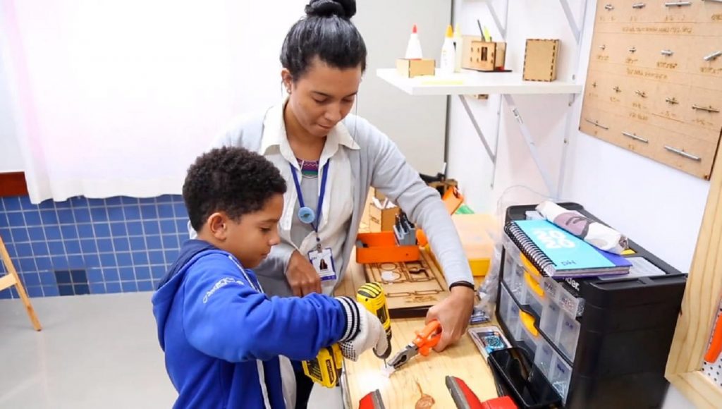Aluno do Ensino Fundamental I do pH com professora, desenvolvendo a autonomia da criança